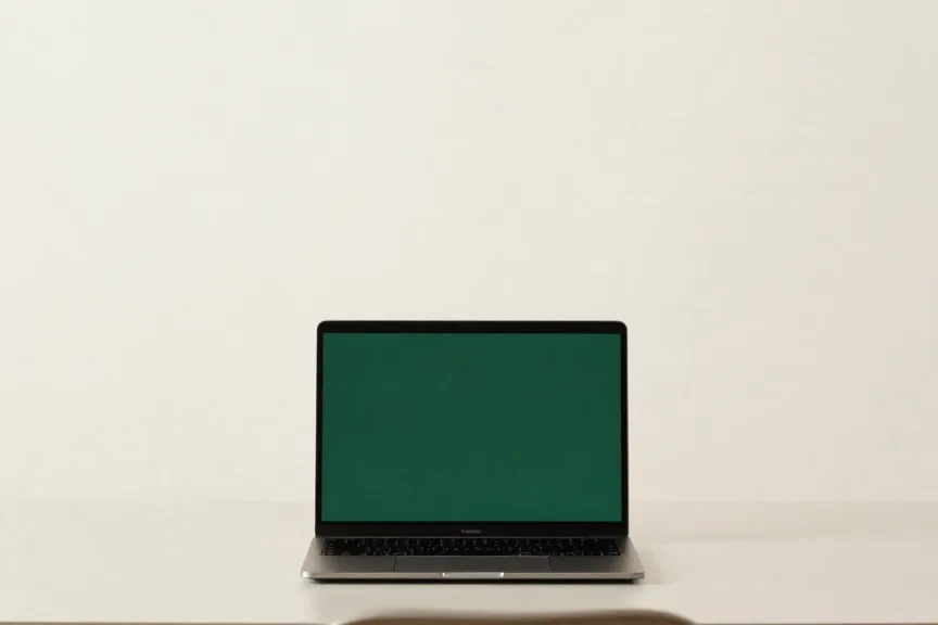 Notebook aberto com a tela em verde sobre uma mesa clara de consultório
