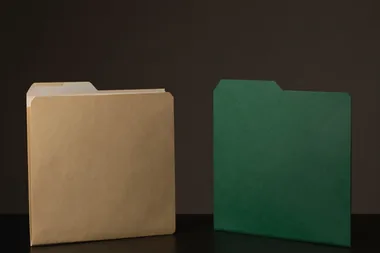 Duas pastas de arquivo em pé, uma de papel kraft e uma verde