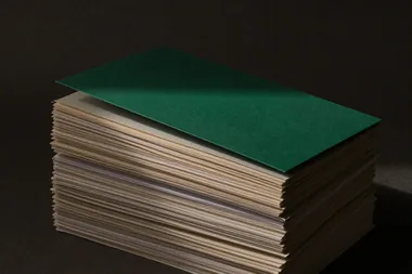 Pilha alta de folhas de papel com uma capa verde no topo
